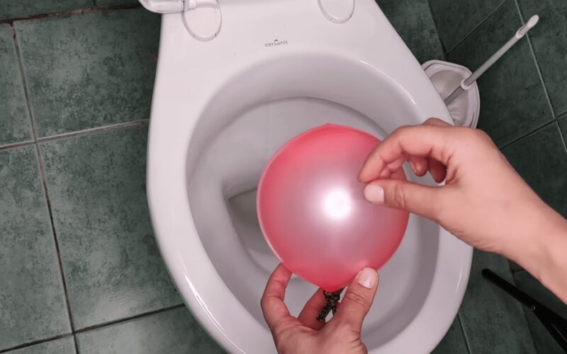 moteris įstumia balioną į tualetą